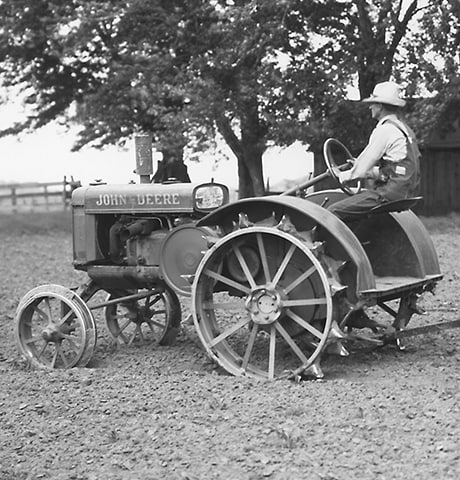 Historický víceúčelový traktor John Deere “GP” táhnoucí kultivátor John Deere č. 7 na poli