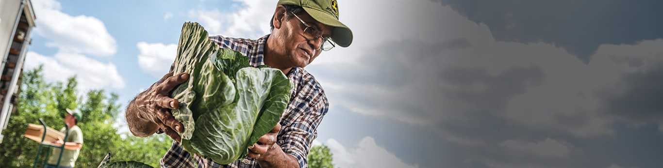 Muž v ochranné přilbě na pracovišti s vybavením John Deere nedaleko