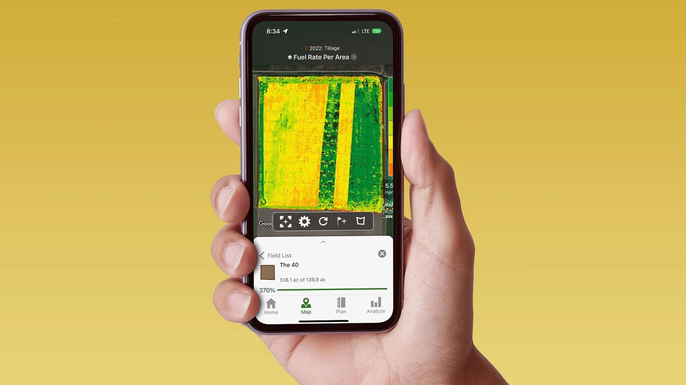 Ruka držící chytrý telefon zobrazující operační středisko John Deere Operations Center s údaji o spotřebě paliva.