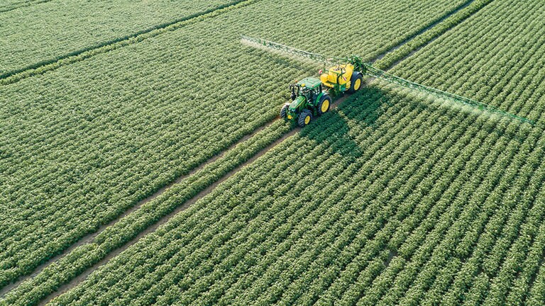 Traktor John Deere řady 6M t&aacute;hne tažen&yacute; postřikovač M700 v&nbsp;bramborov&eacute;m poli