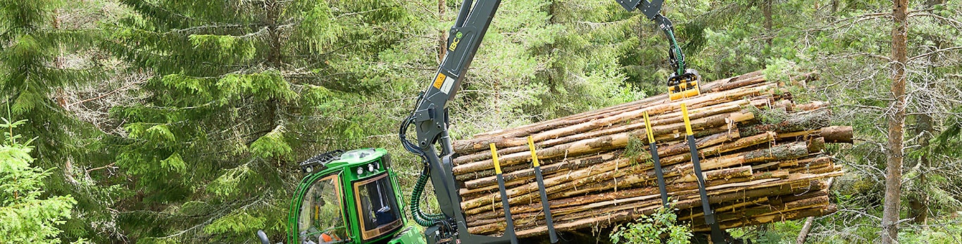 John Deere 1010G manipuluje se dřevem v lese