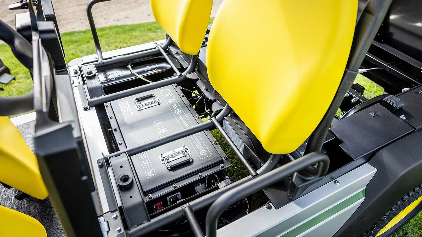 Detailní pohled na dvě lithiové baterie instalované pod jasně žlutými sedadly v elektrickém užitkovém vozidle John Deere Gator GS.