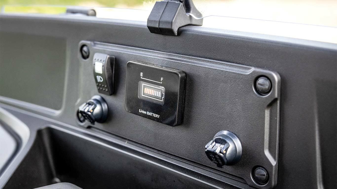 Přístrojová deska elektrického modelu John Deere Gator GS s ukazatelem stavu baterie a napájecími porty.
