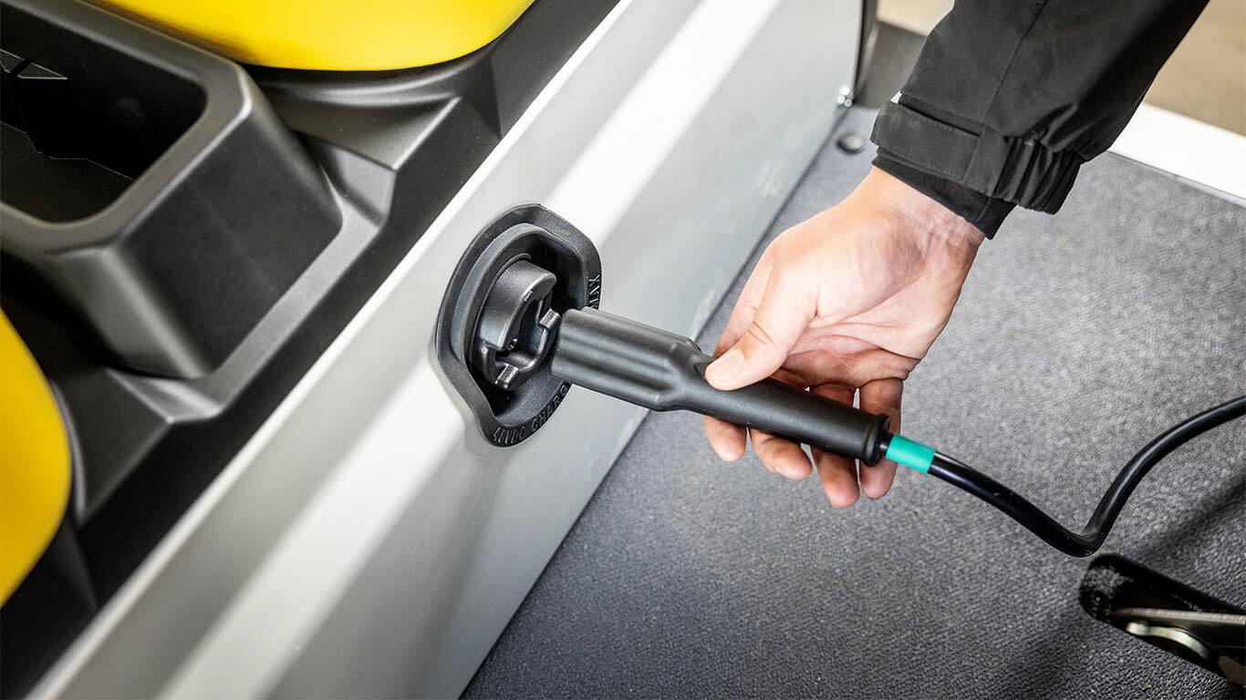 Ruční zapojení nabíjecího kabelu do bočního portu elektrického užitkového vozidla John Deere Gator GS.