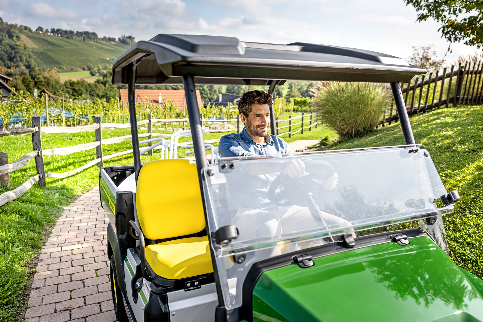 Detailní pohled na interiér vozidla John Deere Gator GS se žlutými sedadly a volantem