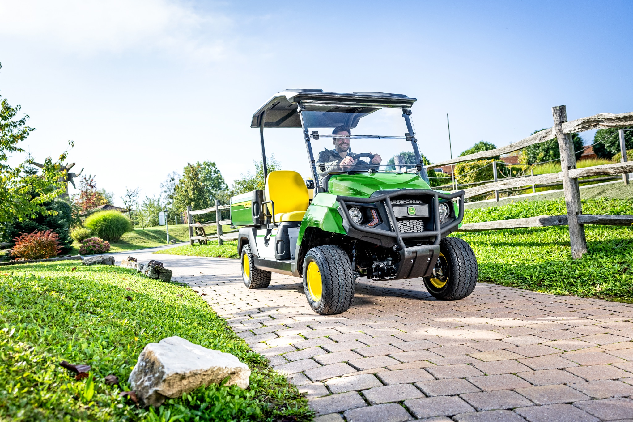 Užitkové vozidlo Gator GS při jízdě po zpevněné cestě v upravené krajině