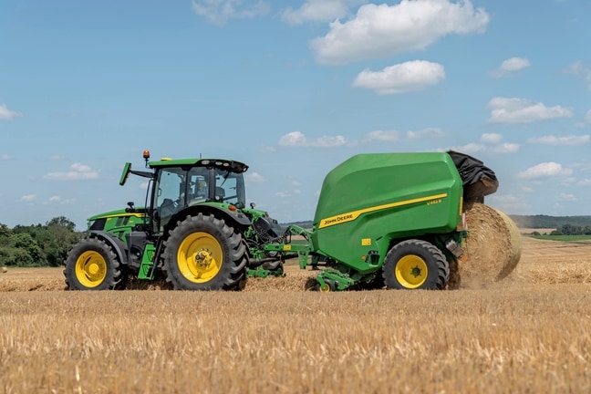 John Deere V452R na slámovém poli tažený strojem John Deere 6R 150 vyhazující balík