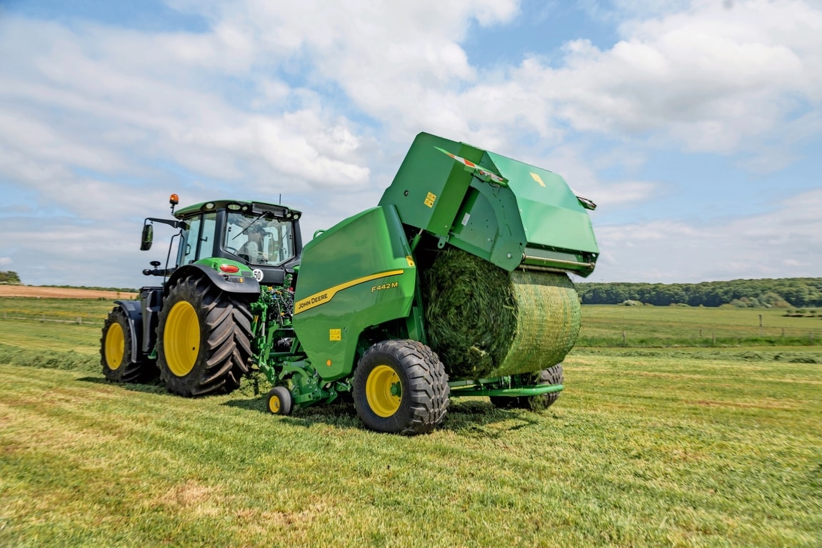 Sběrací lis John Deere F442M tažený traktorem John Deere 6M vyhazující balík trávy